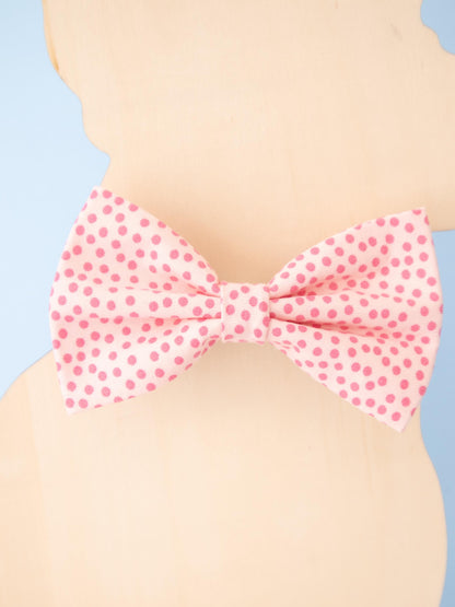 Pink polka dot bow tie on a dog model against a blue and beige background