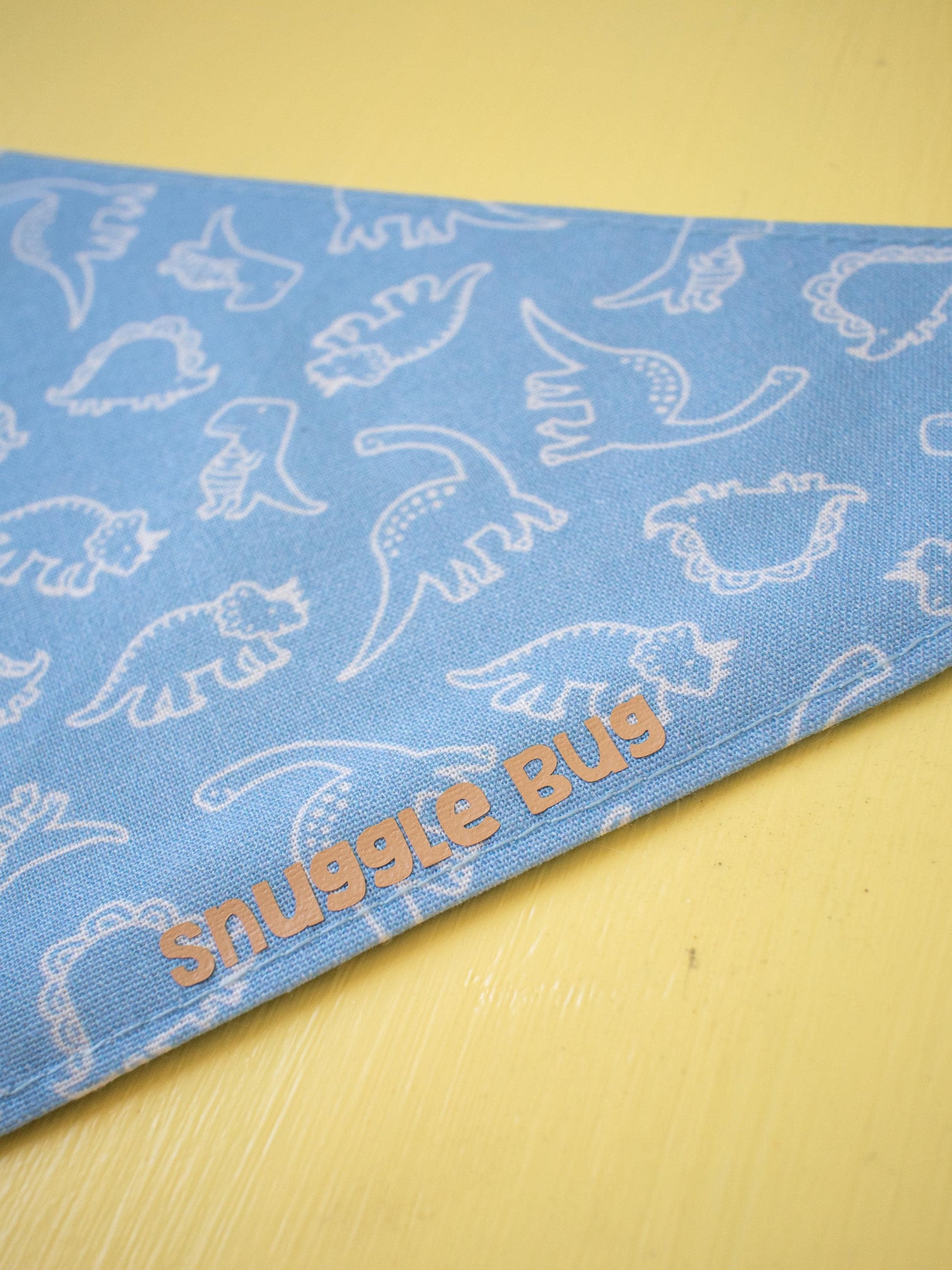 Blue bandana with white dinosaur patterns and 'Snuggle Bug' text on a yellow background