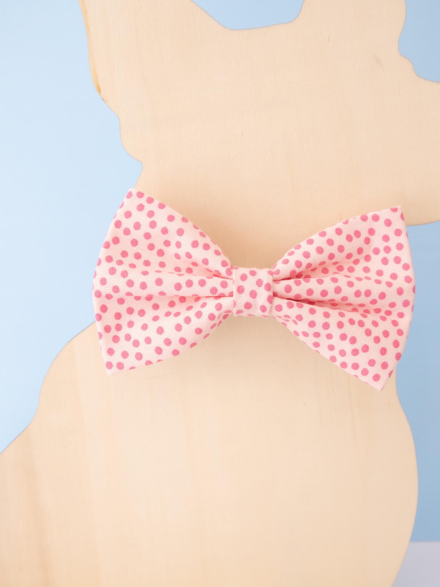 Pink polka dot bow tie on a dog model against a light blue background