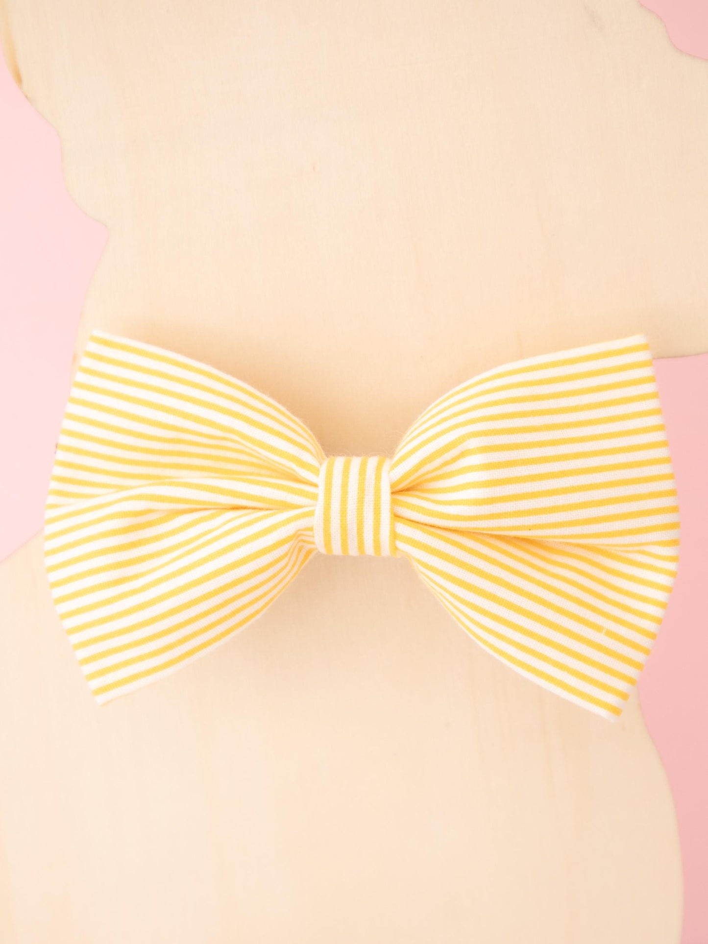 Yellow striped bow on a pink background