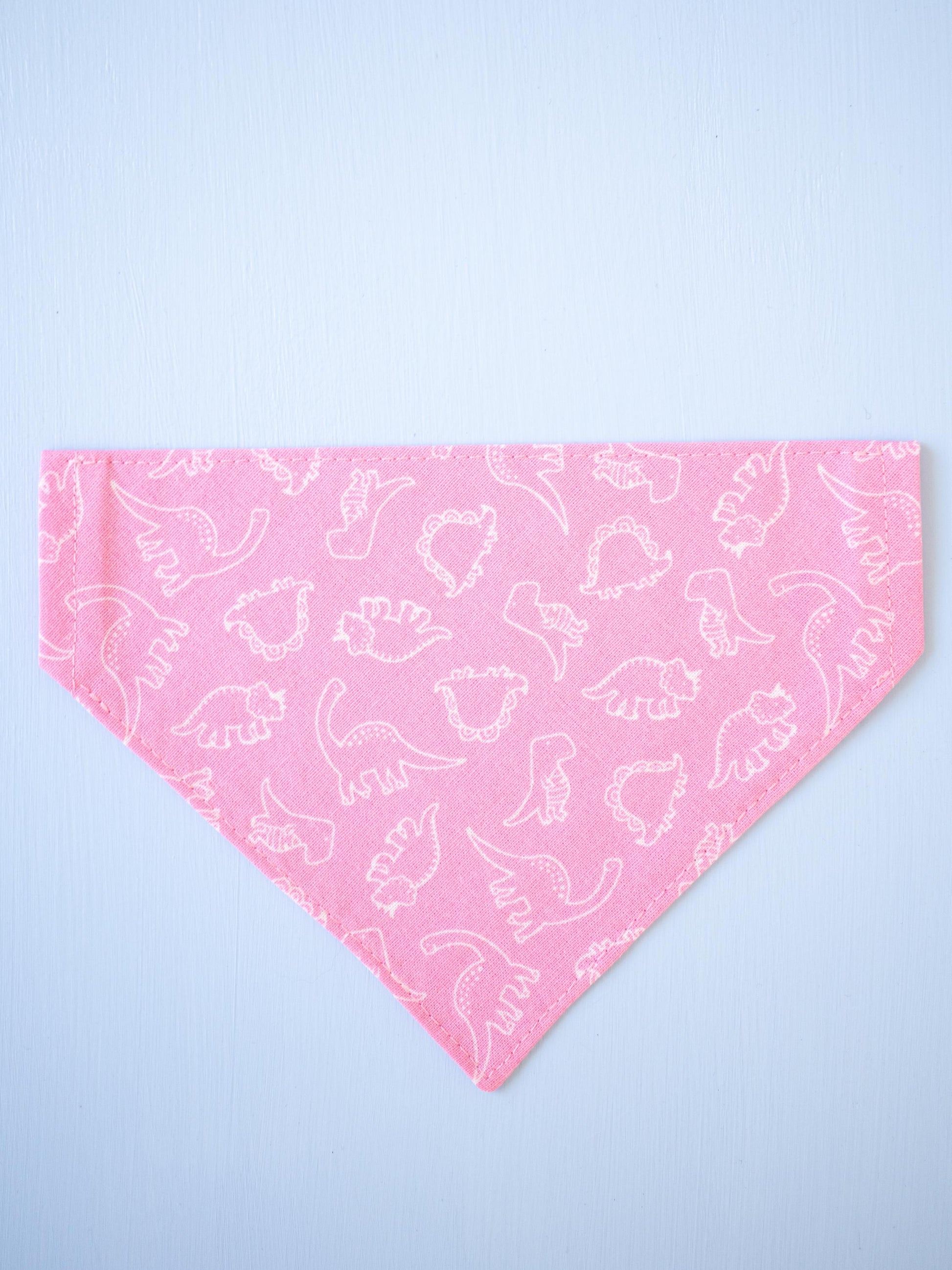 Pink bandana with white dinosaur pattern on a light blue background