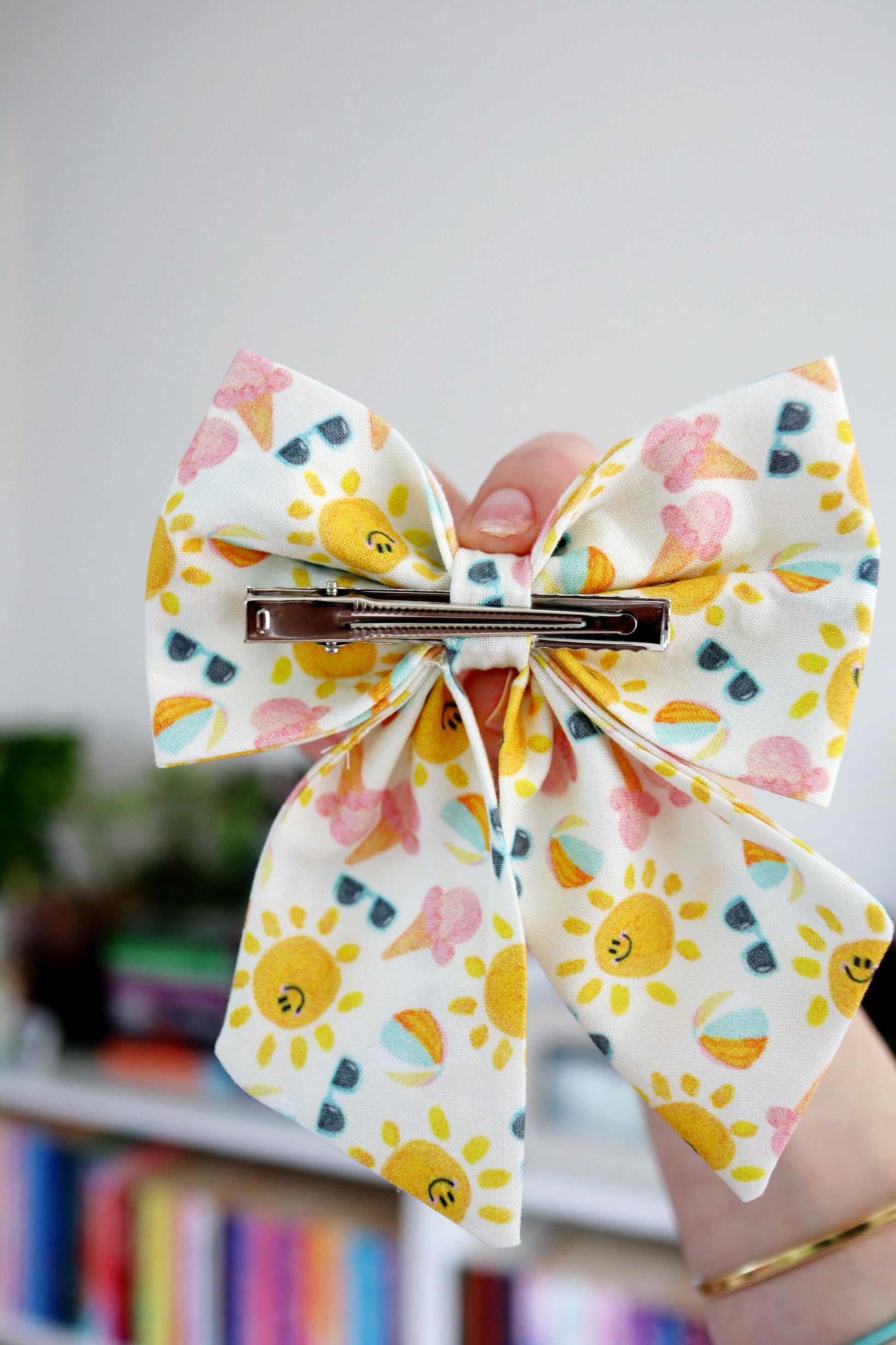 Colorful bow held by a hand with a blurred bookshelf background