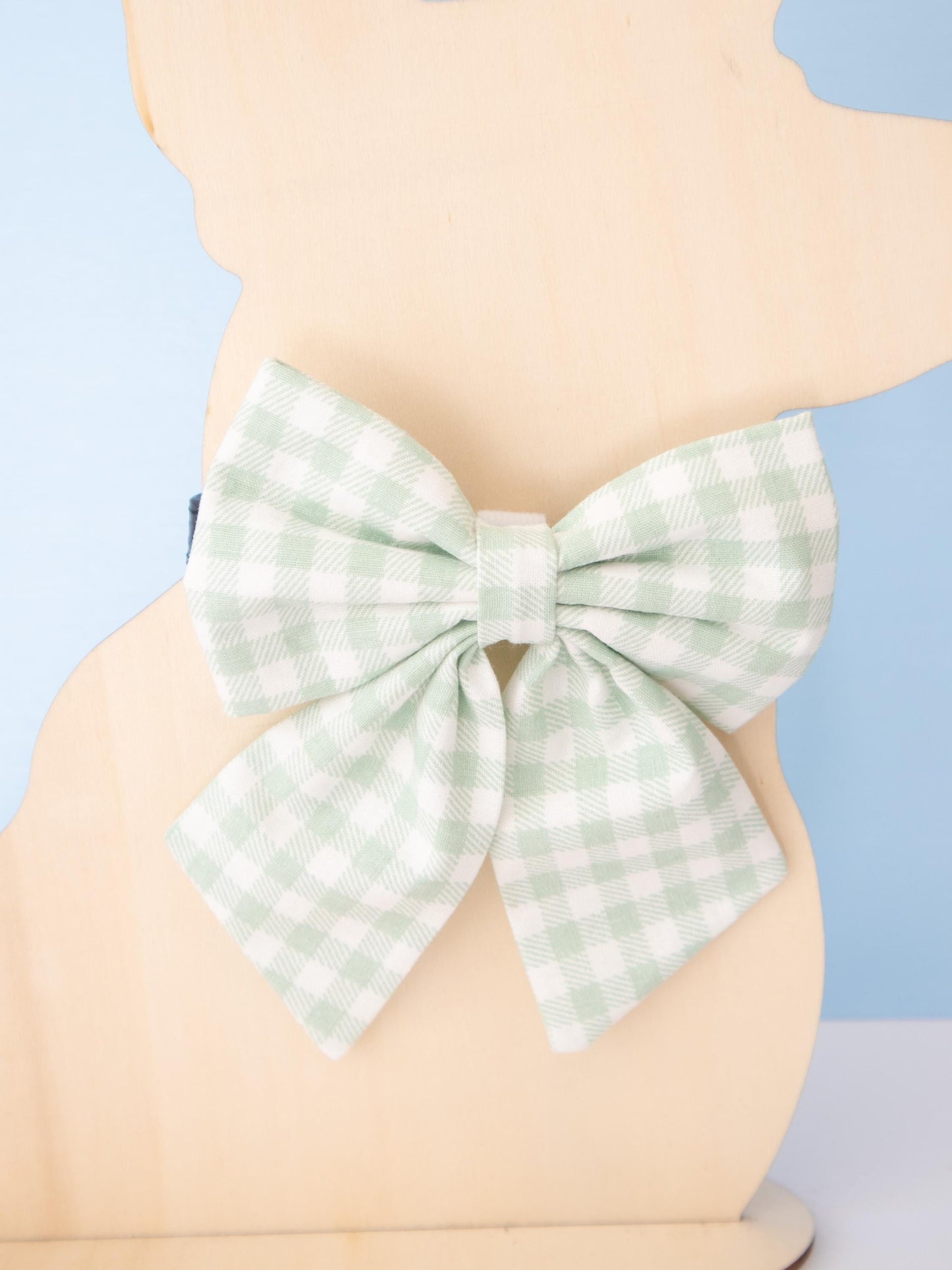 Green checkered bow on a mannequin against a light blue background