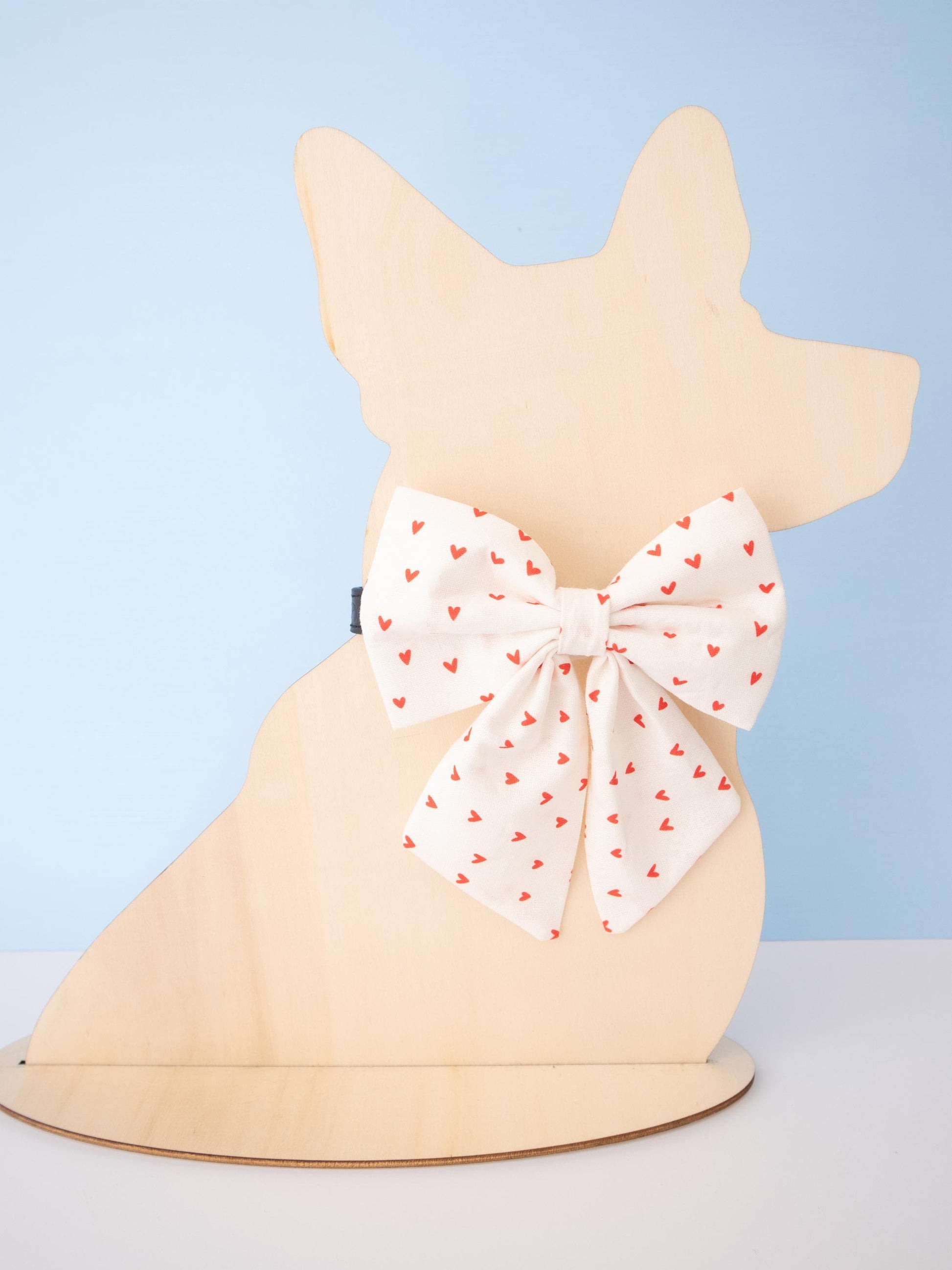 Dog-shaped Mannequin with a white sailor bow featuring red hearts on a light blue background