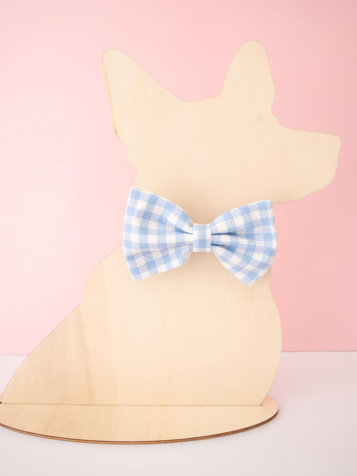 Dog-shaped Mannequin with a blue checkered bow tie on a pink background