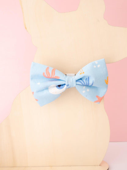 Light blue bow tie with seagull character pattern on a pastel background