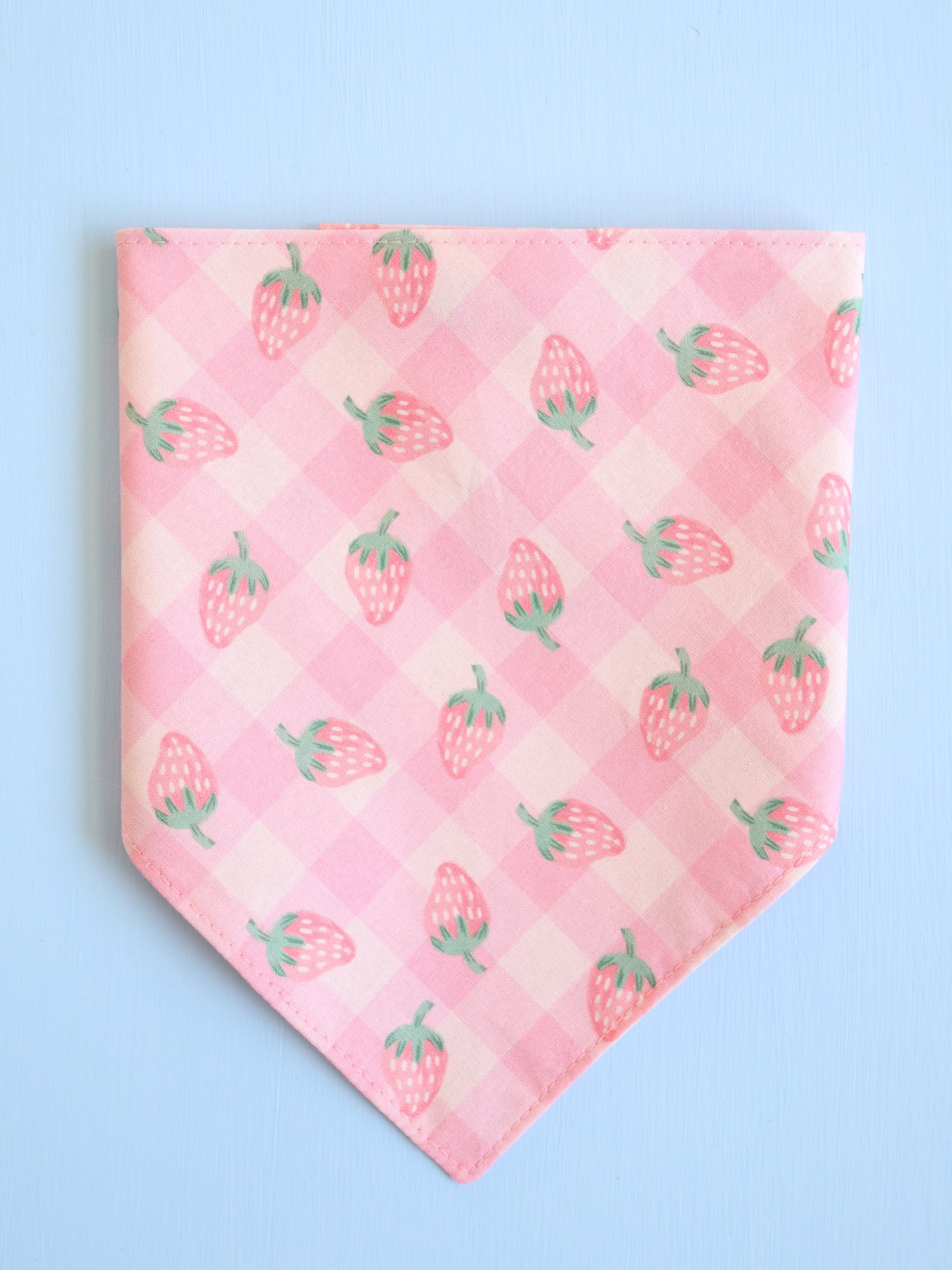 Pink bandana with strawberry pattern on a light blue background