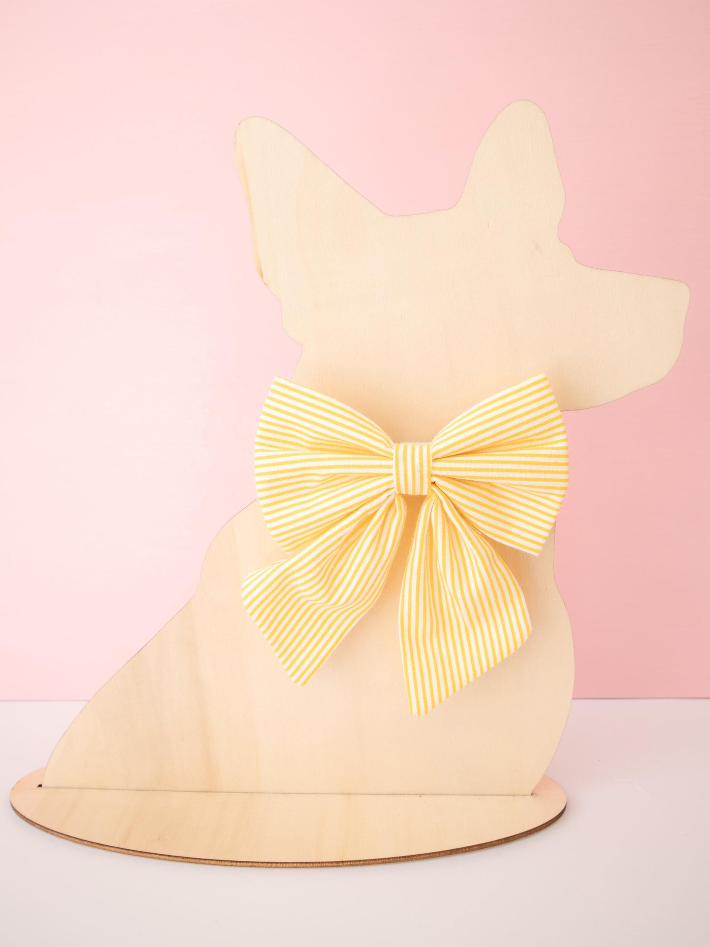 Dog-shaped model with a large yellow bow on a pink background