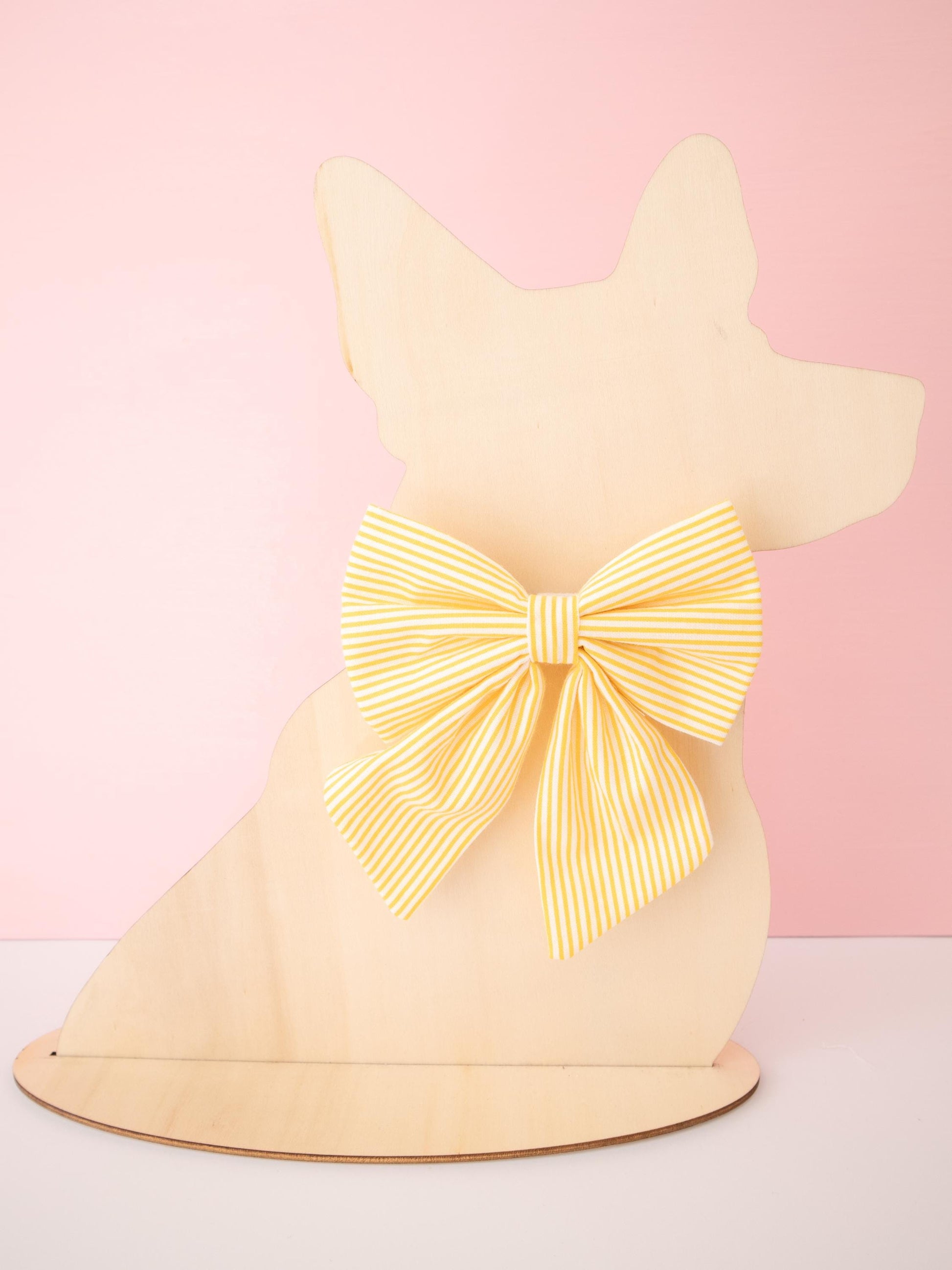 Dog-shaped model with a large yellow bow on a pink background
