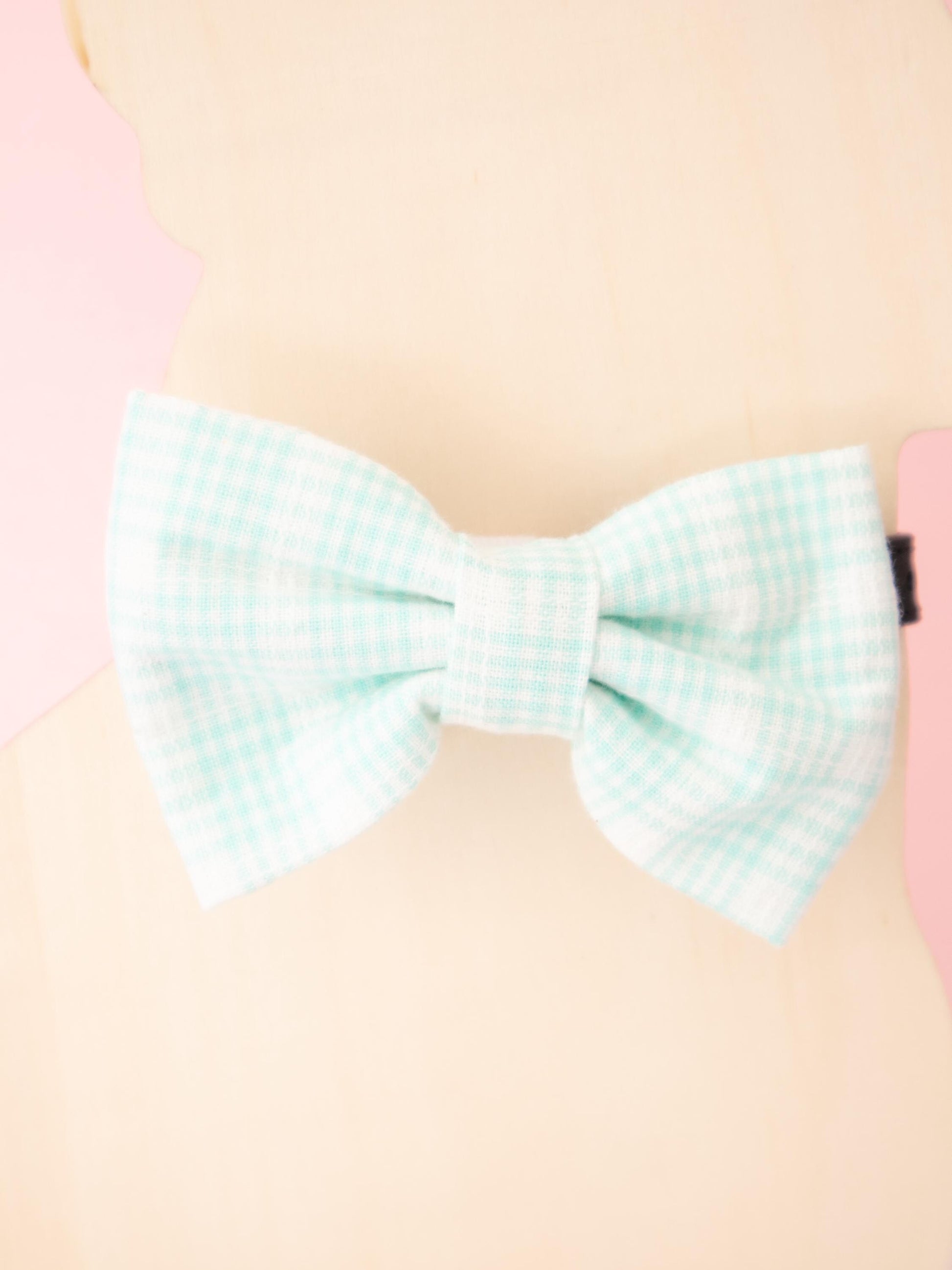 Pastel green checkered bow on a pink background