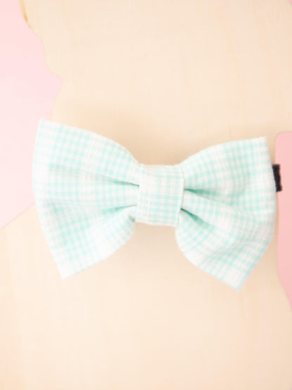 Pastel green checkered bow on a pink background