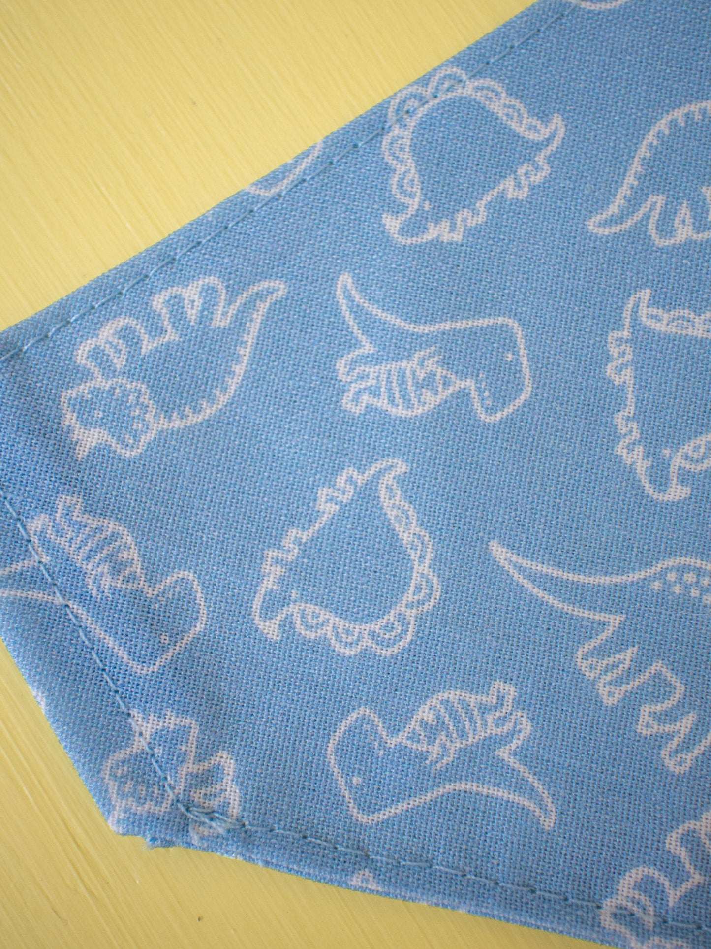 Blue fabric with white dinosaur patterns on a yellow surface