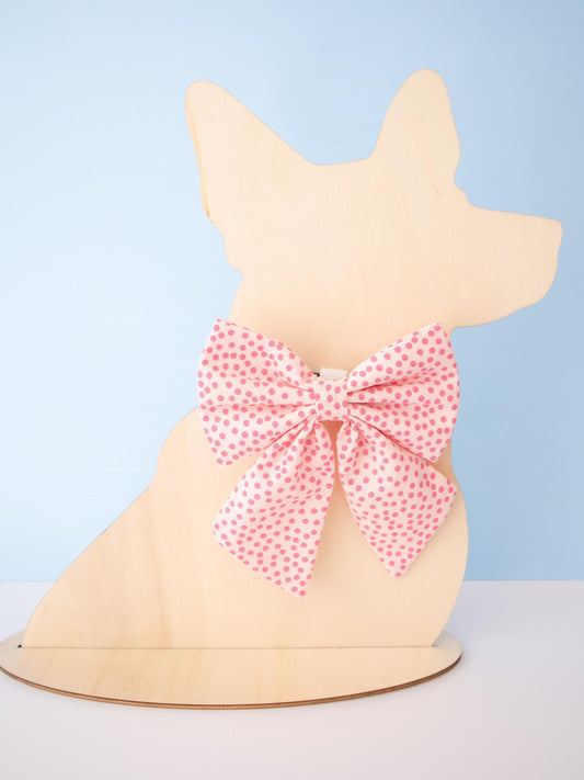Dog-shaped model with a pink polka dot bow on a light blue background