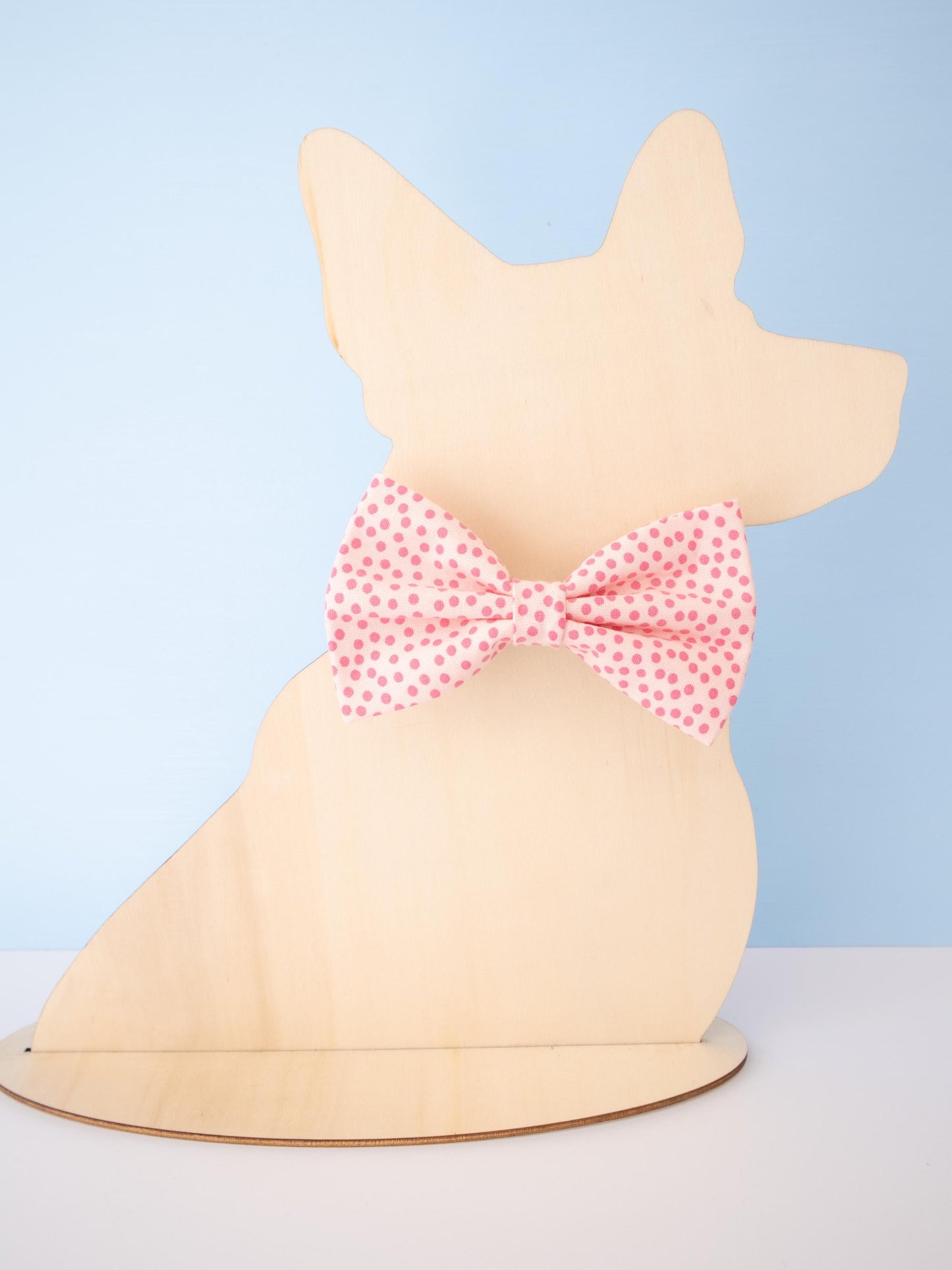 Dog-shaped model with a pink polka dot bow on a light blue background