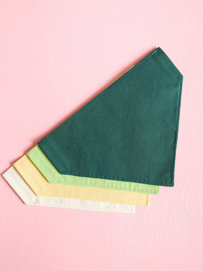 Green, yellow, and cream fabric over the collar bandanas on a pink background