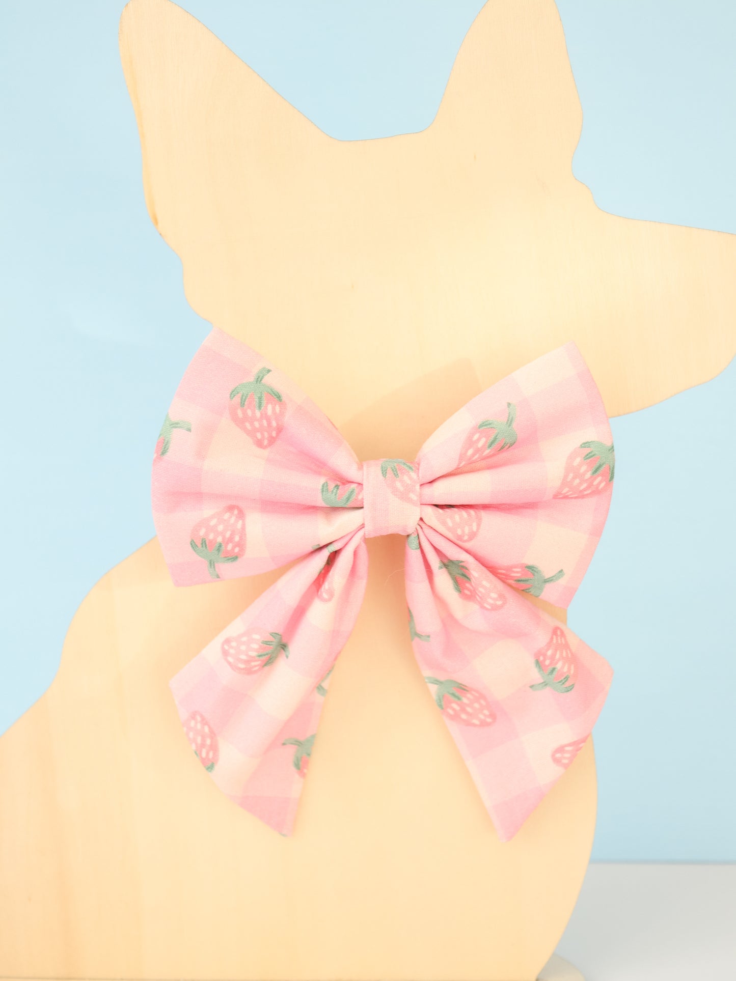 Pastel yellow dog model with a pink bow and strawberry pattern on a light blue background