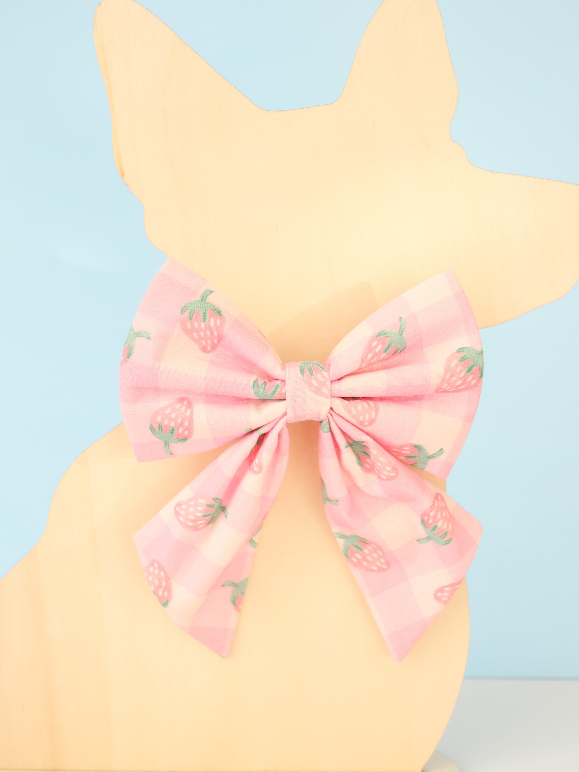 Pastel yellow dog model with a pink bow and strawberry pattern on a light blue background