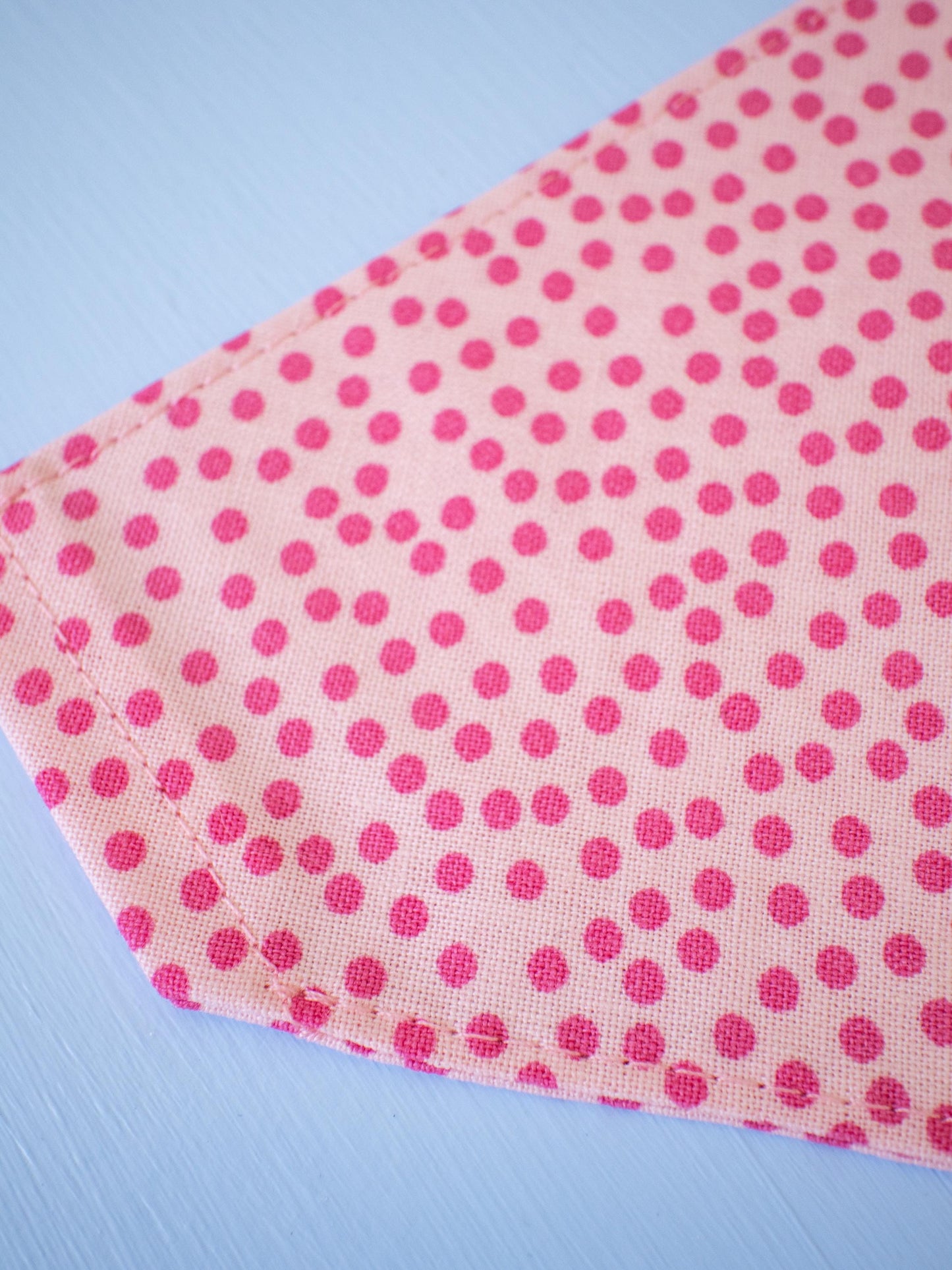 Pink polka dot fabric on a light blue background