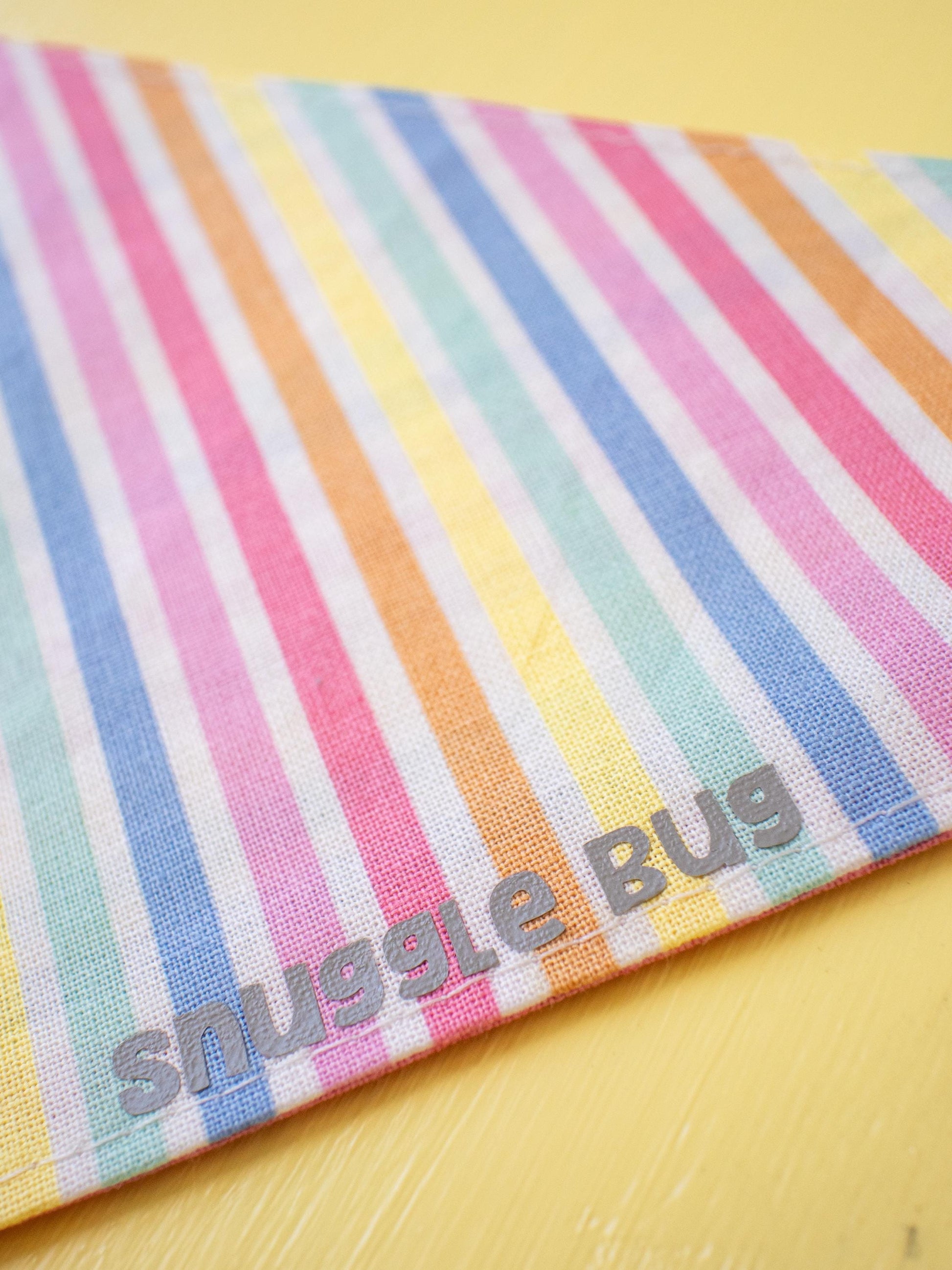 Colorful striped fabric with 'snuggle bug' branding on a yellow background
