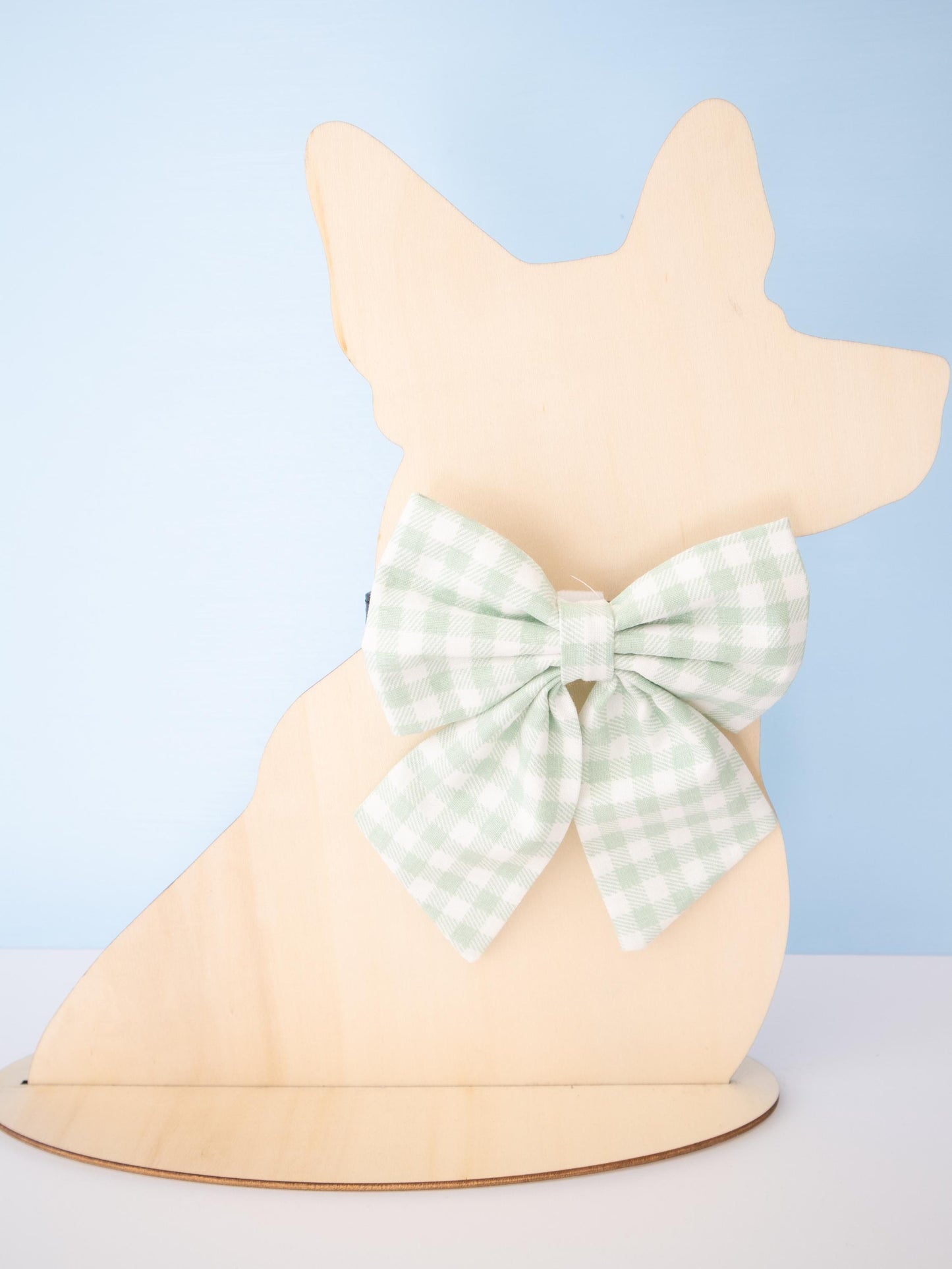 Dog-shaped Mannequin with a green checkered bow on a light blue background