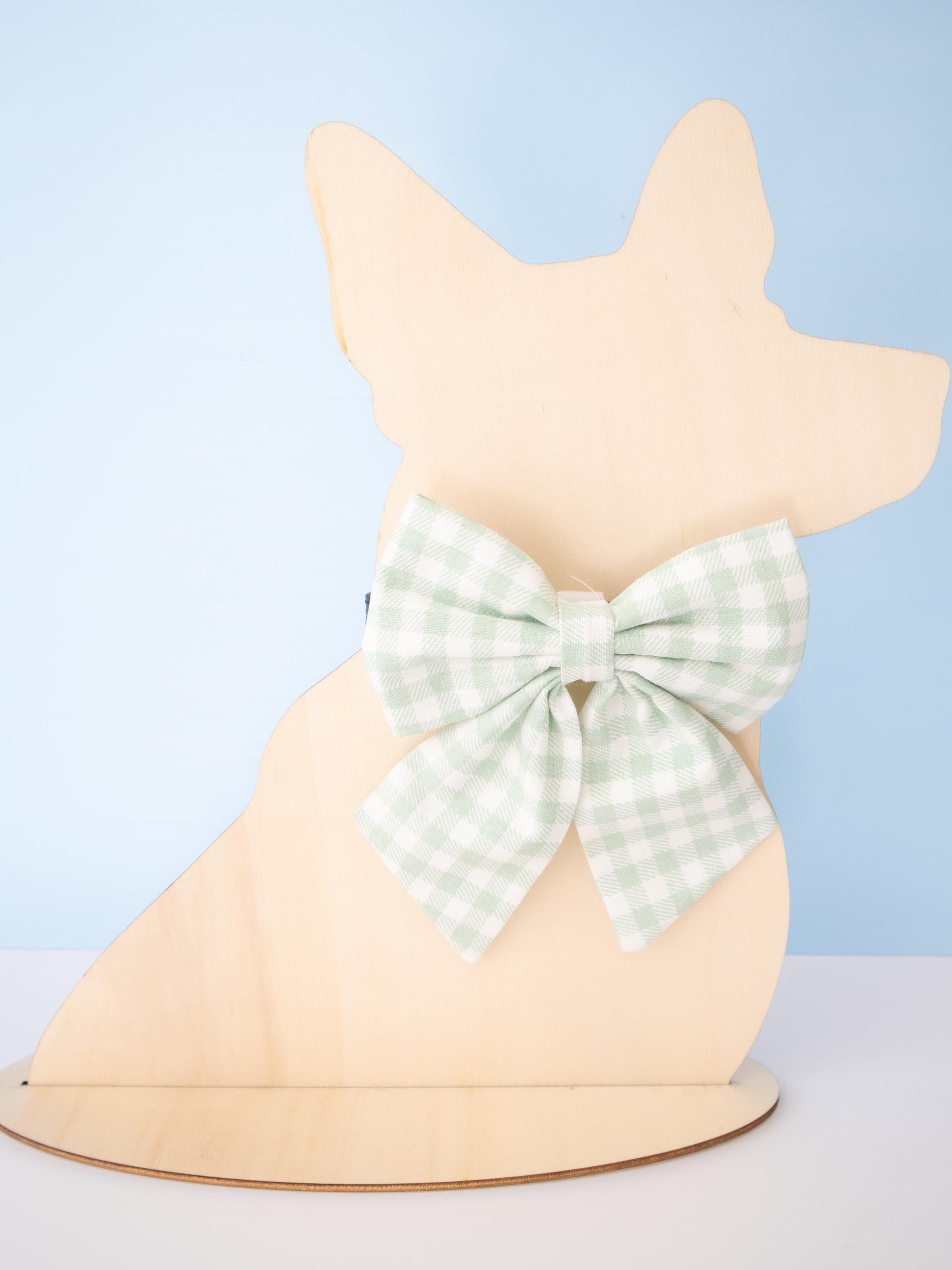 Dog-shaped Mannequin with a green checkered bow on a light blue background