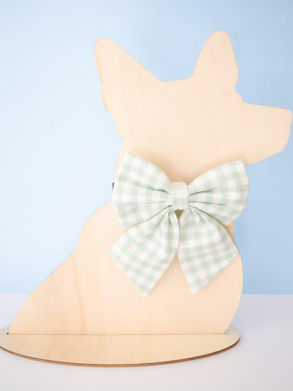 Dog-shaped Mannequin with a green checkered bow on a light blue background
