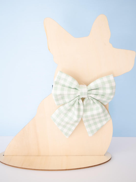 Dog-shaped Mannequin with a green checkered bow on a light blue background