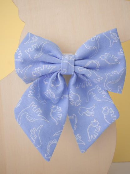 Large blue bow with white dinosaur patterns on a mannequin against a yellow background