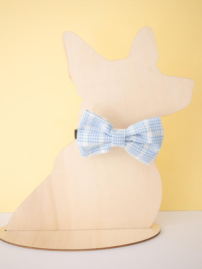 Mannequin head with a blue checkered bow tie against a yellow background