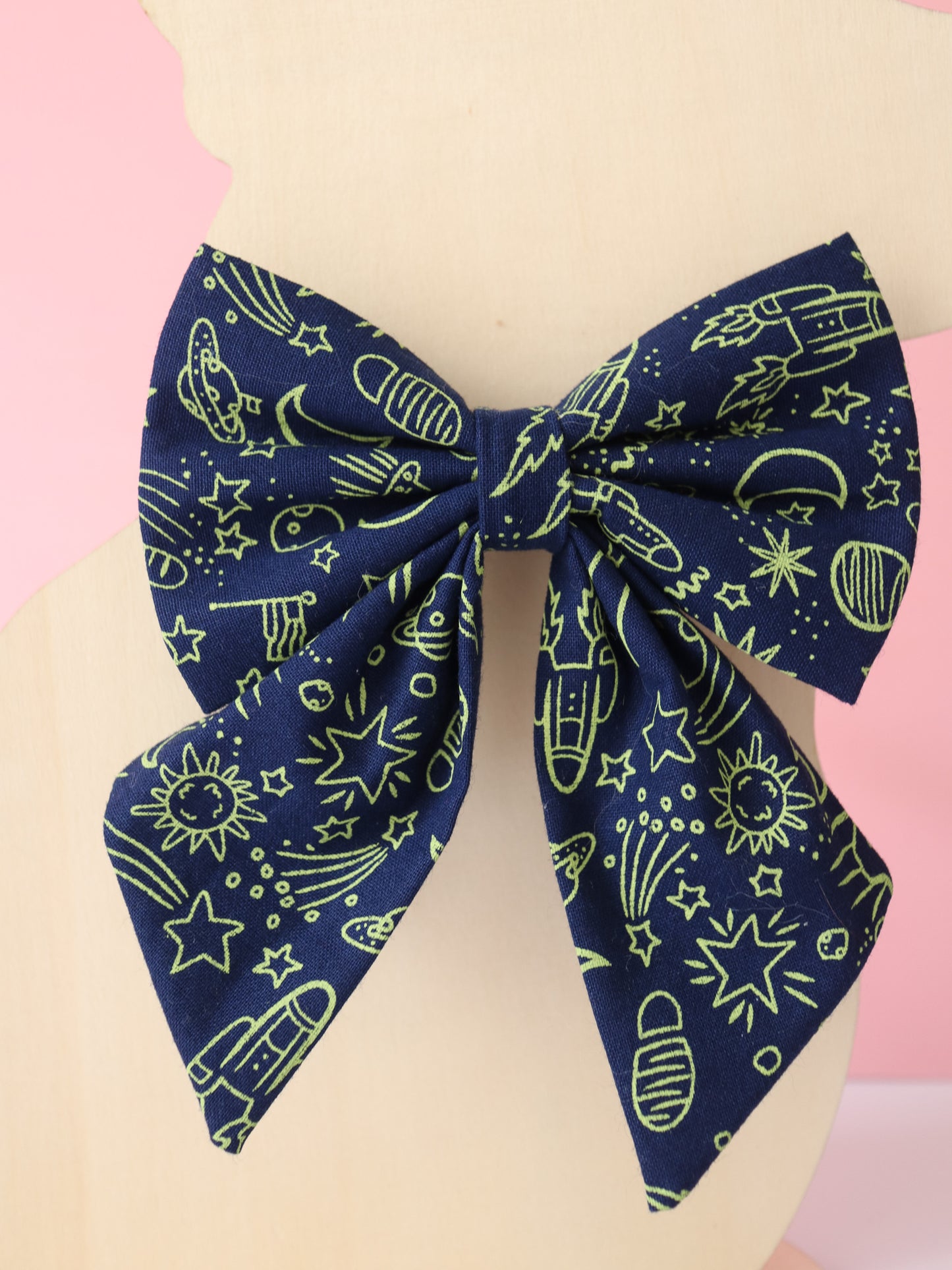 Navy blue bow with space-themed pattern on a mannequin against a pink background