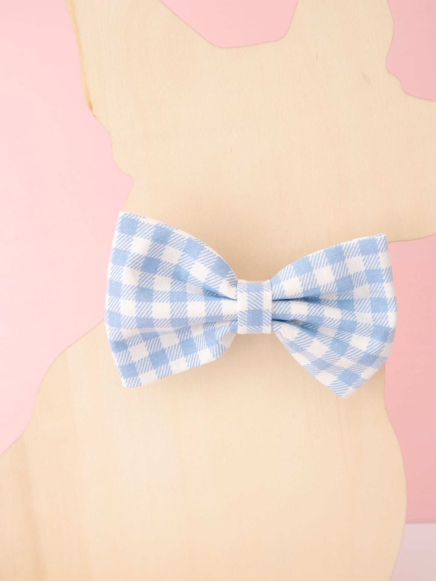 Blue and white checkered bow tie on a beige and pink background