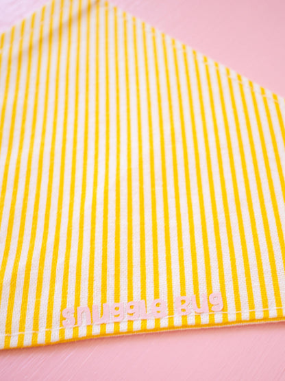 Yellow and white striped fabric with 'Snuggle Bug' branding on a pink background