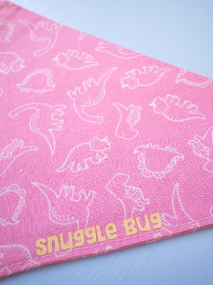 Pink bandana with white dinosaur patterns and 'snuggle bug' text on a light blue background