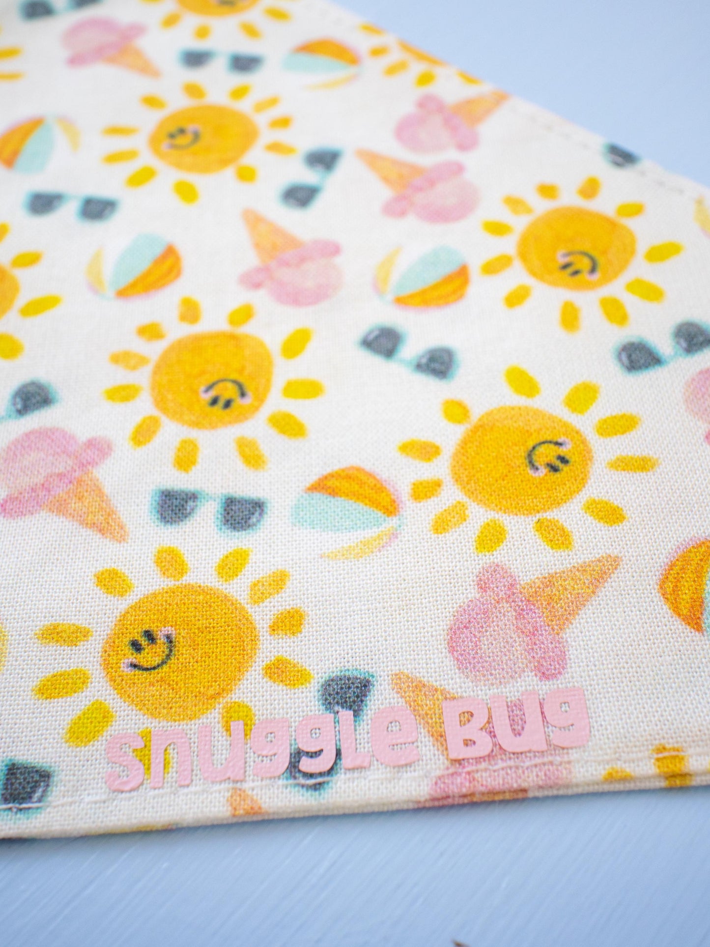 Fabric with sun and ice cream pattern and 'smiggle bug' branding on a blue background