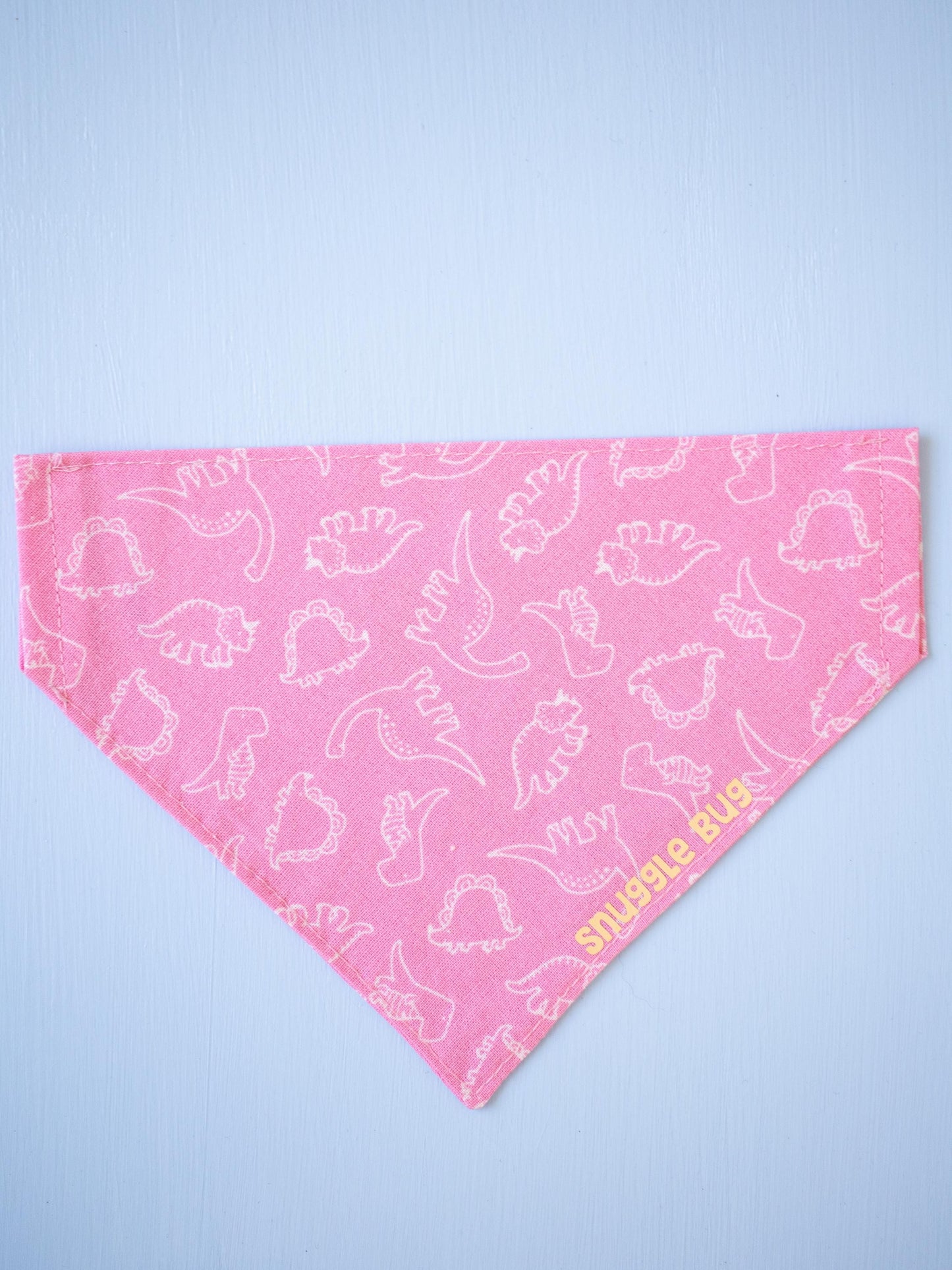 Pink bandana with white dinosaur pattern on a light blue background