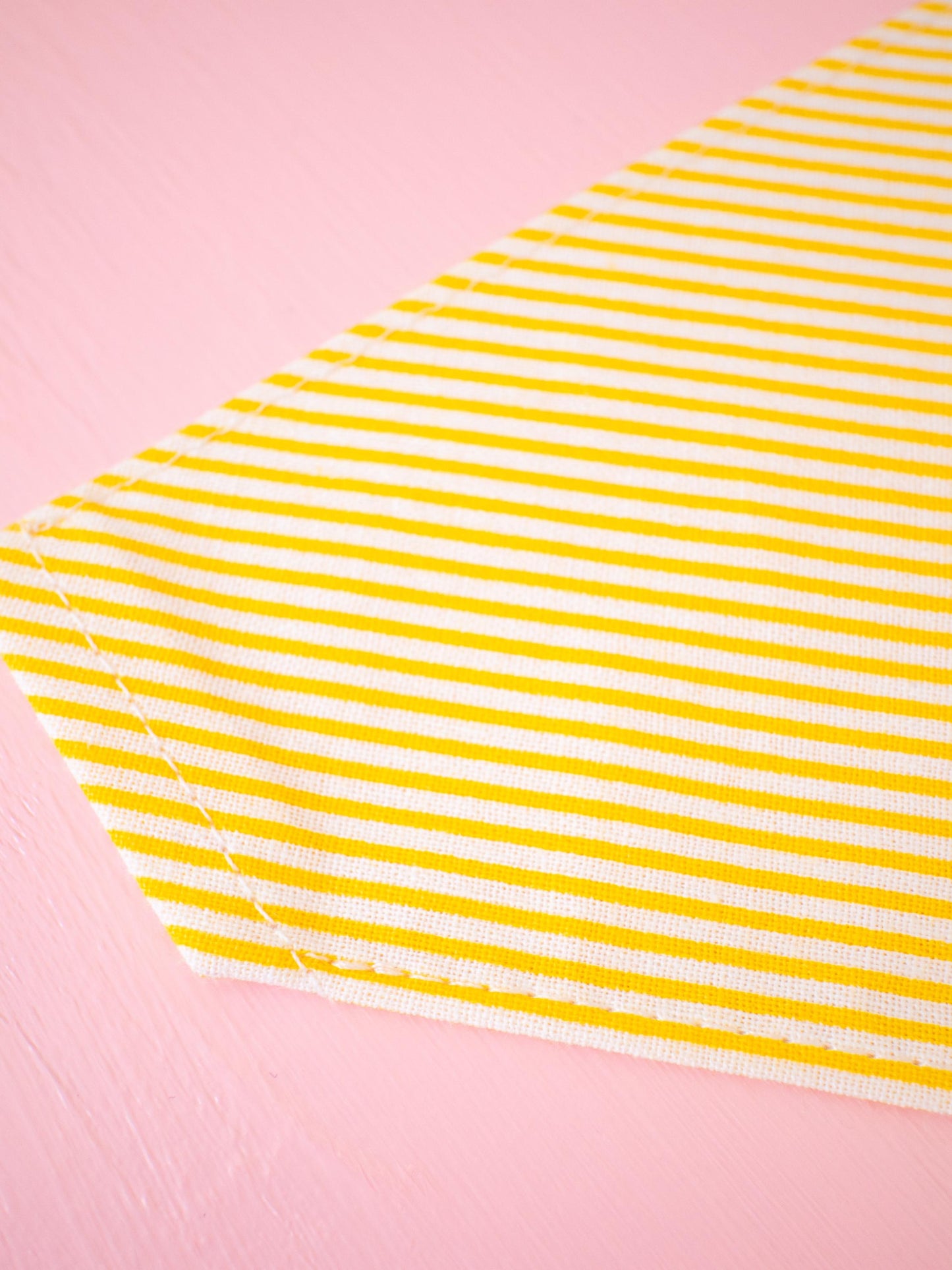Yellow and white striped bandana on a pink background