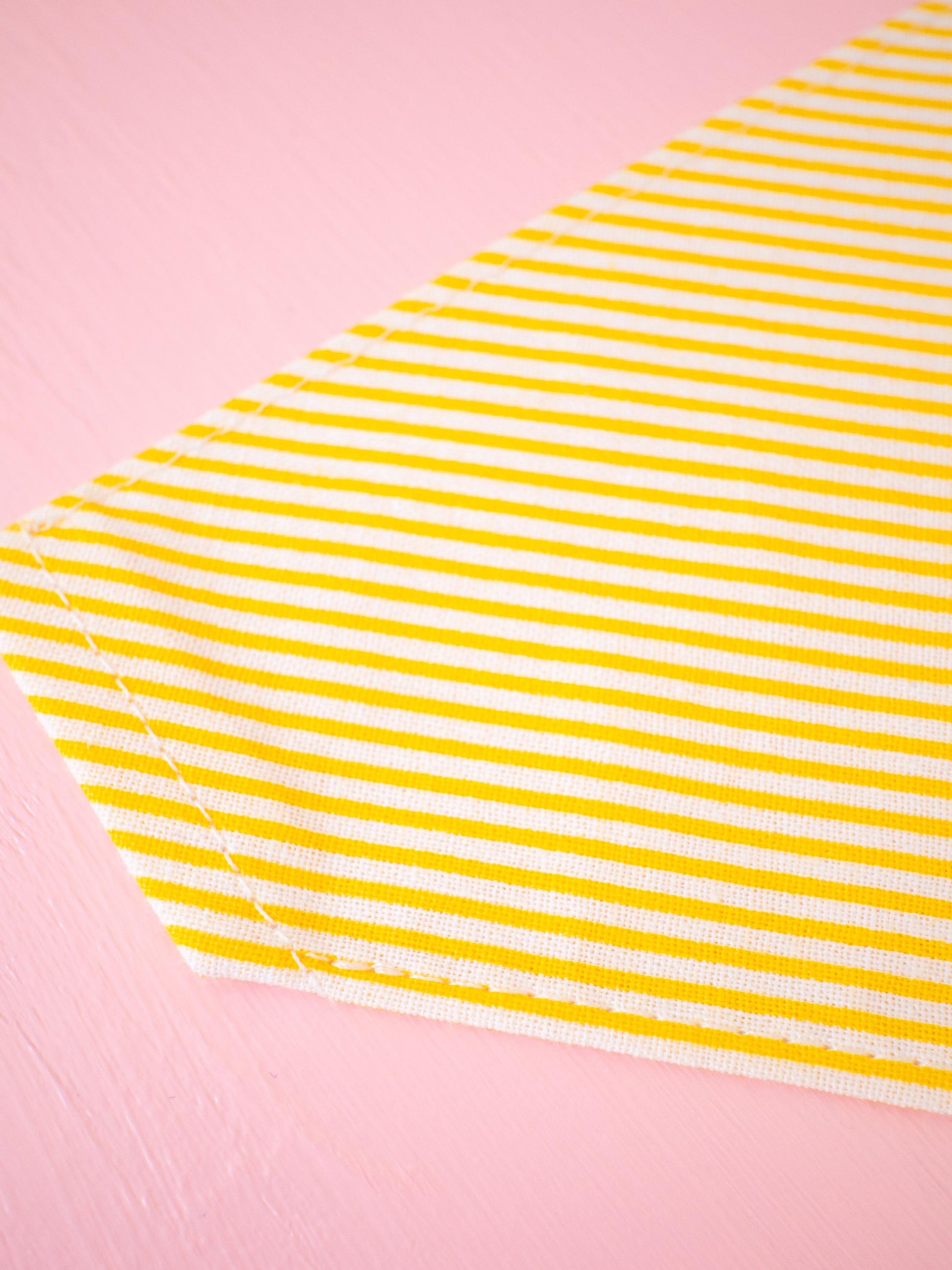 Yellow and white striped bandana on a pink background