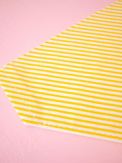 Yellow and white striped bandana on a pink background