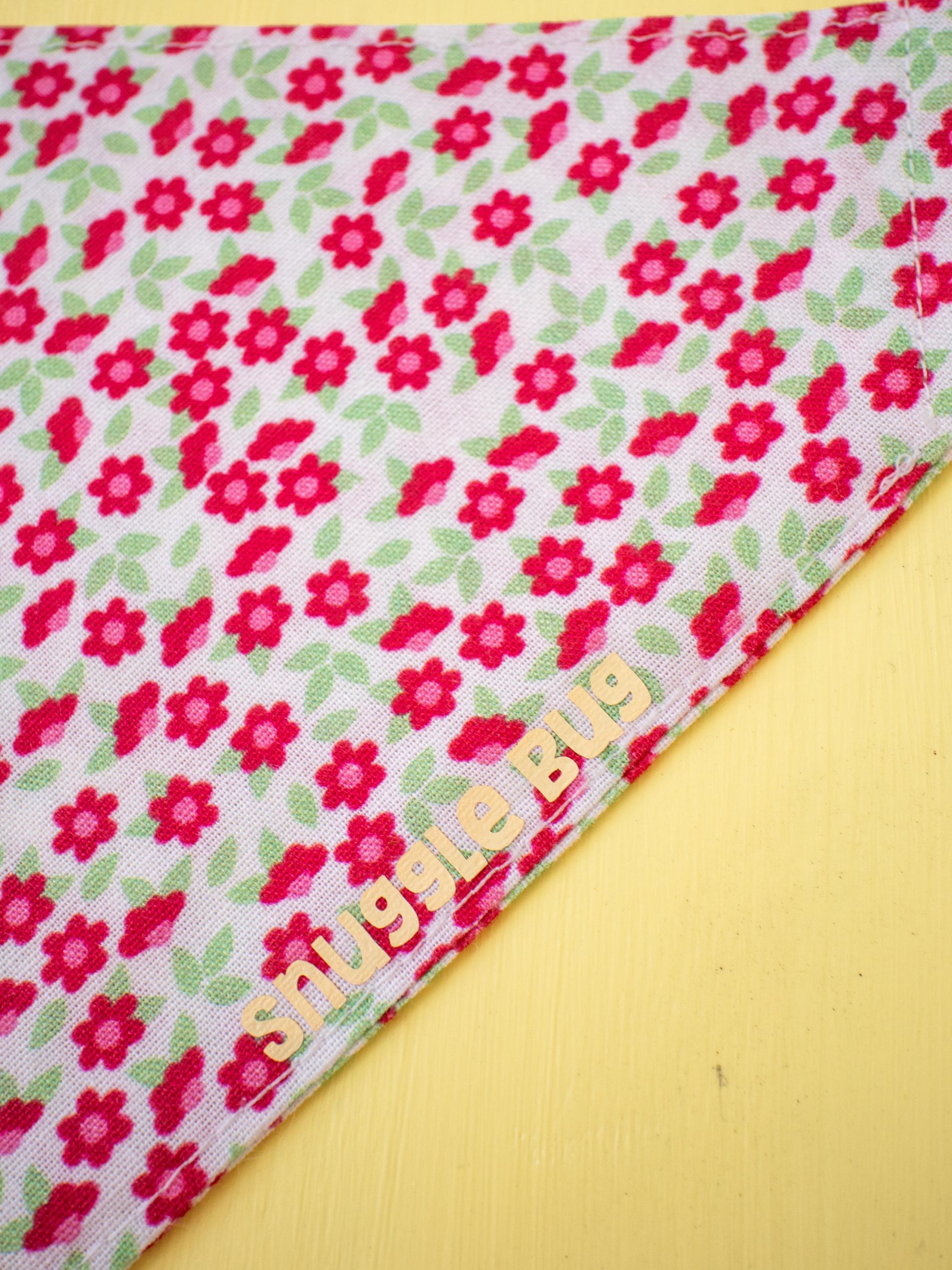 Floral fabric with red flowers and green leaves on a yellow background