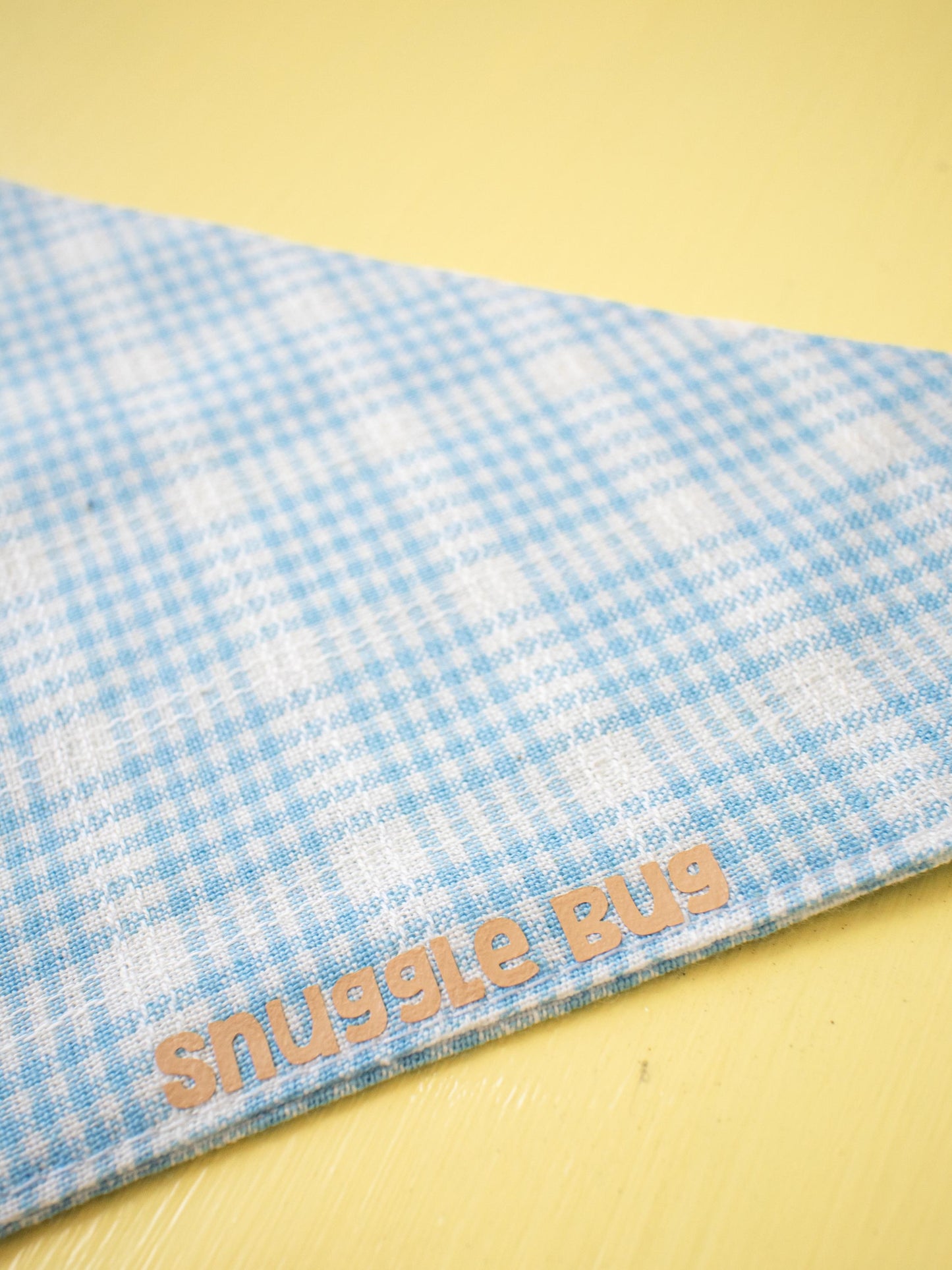 Blue checkered blanket with 'Snuggle Bug' text on a yellow background