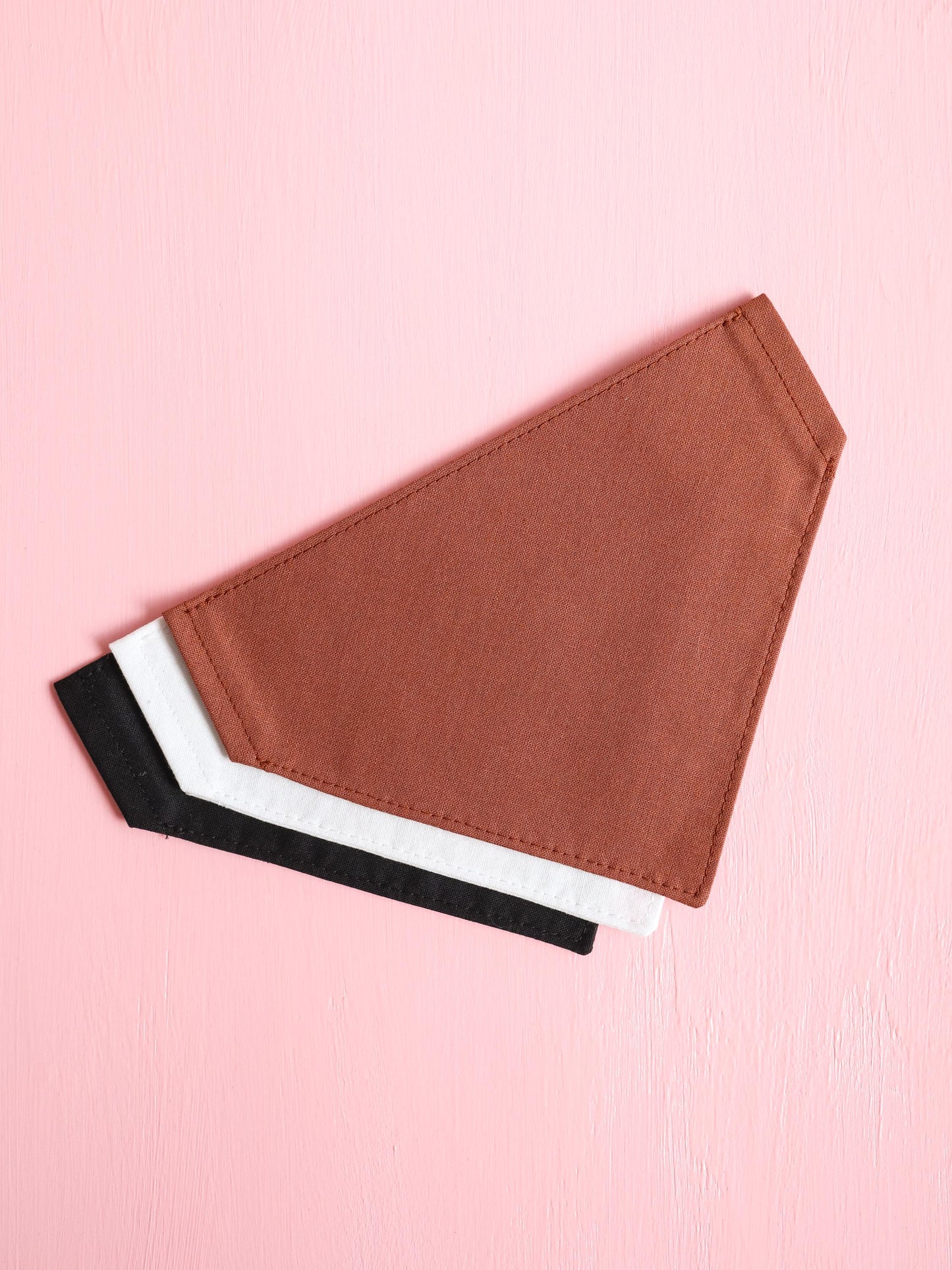 Brown, white and black over the collar pet bandanas on a pink background