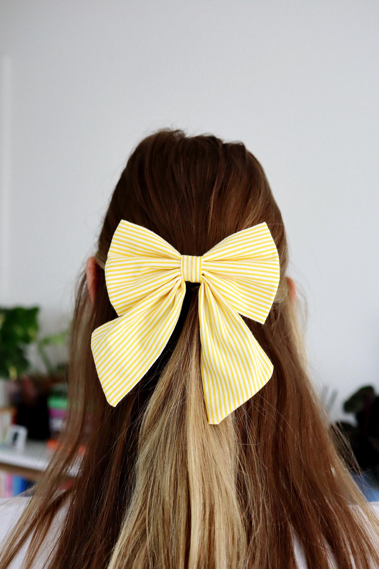 Person with long hair wearing a large yellow bow in the back