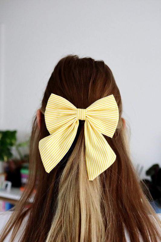Person with long hair wearing a large yellow bow in the back