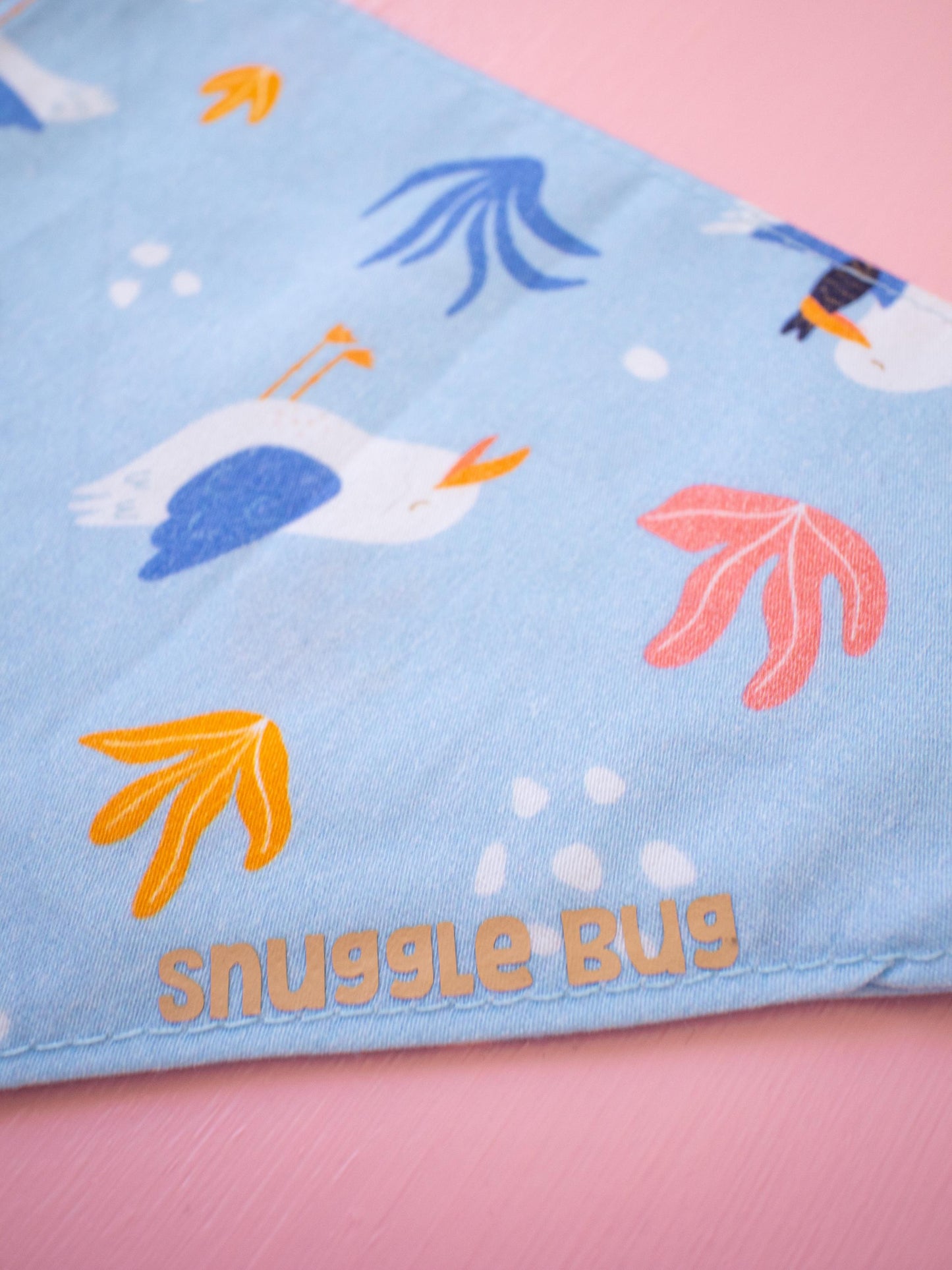 Dog Bandana with cartoon seagulls and 'snuggle bug' text on a pink background